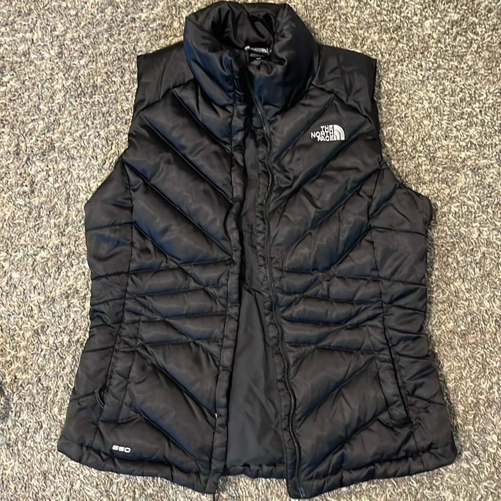 North face down vest, lightly worn, armpit of left arm has small tear.